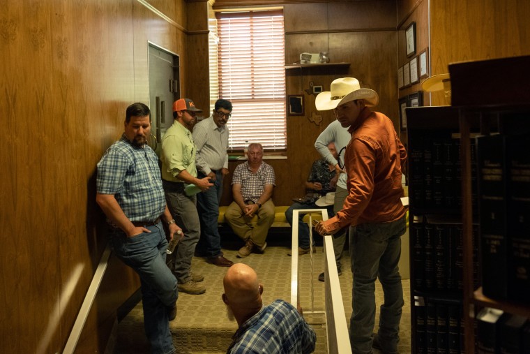 Loving County residents, including Commissioner Raymond King, left, wait to go through the security check by the Loving County Sheriff's Department before the commissioners court meeting on June 13.