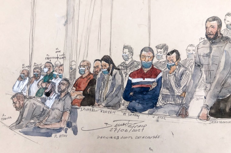 Salah Abdeslam, right, stands next to the 13 other defendants in front of Paris' special assize court during the trial of the November 2015 attacks that saw 130 people killed at the Stade de France in Saint-Denis, bars, restaurants and the Bataclan concert hall in Paris in this sketch made on June 27, 2022.