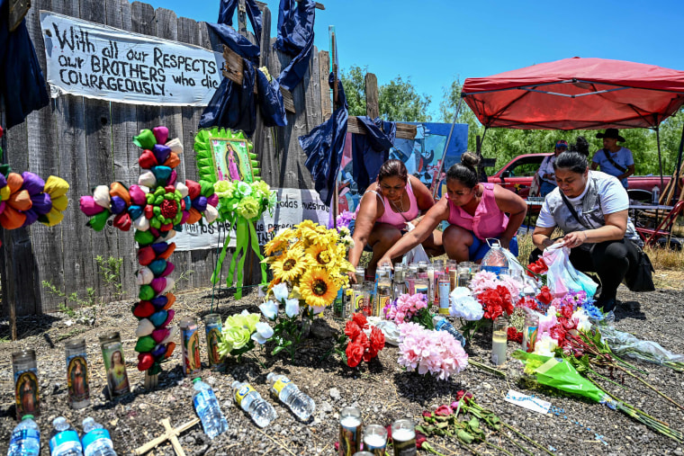 Image: People place flowers and candles at a makeshift memorial where a tractor-trailer was discovered with migrants inside, outside San Antonio, Texas, on June 29, 2022.
