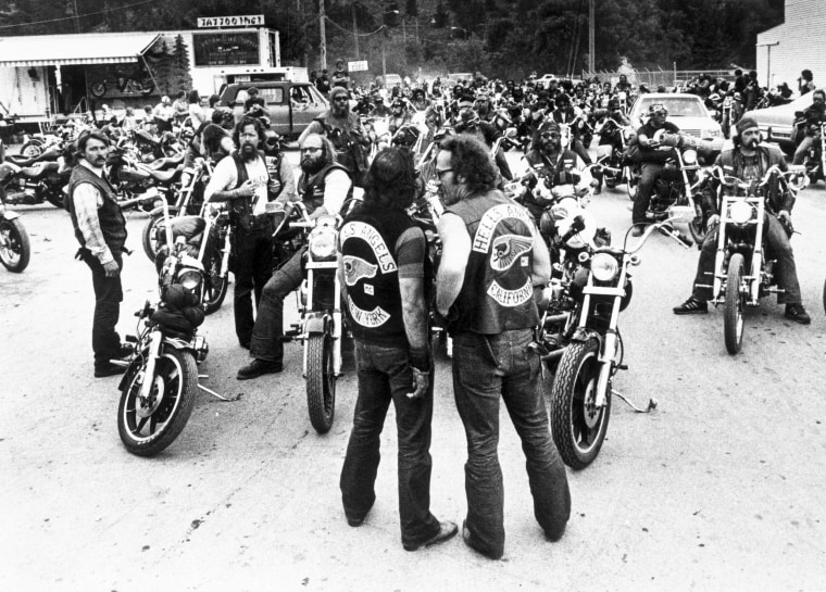Image: Sonny Barger, right, and an unidentified member from the New York chapter stand in front of a group of Hell's Angels members on motorcycles.