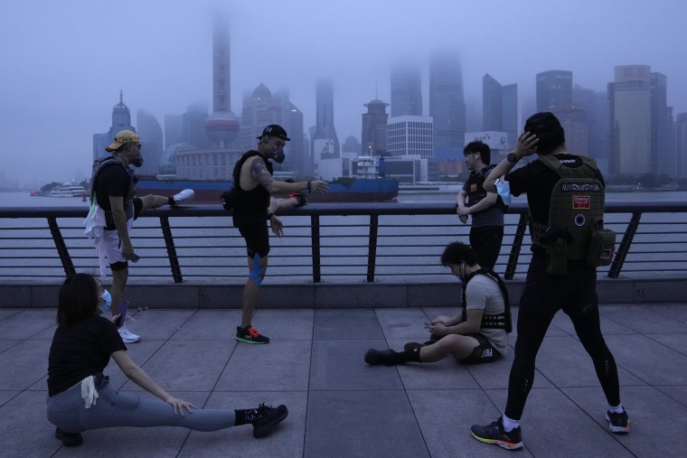 Residents wearing masks exercise along the Bund as day breaks in Shanghai on Wednesday, which marked the official end of a two-month lockdown.