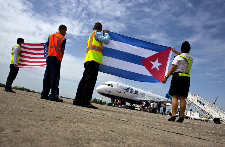 Trabajadores del aeropuerto reciben el vuelo 387 de JetBlue, el primer vuelo comercial entre Estados Unidos y Cuba en más de medio siglo, sosteniendo una bandera de Estados Unidos, y una bandera nacional cubana, en la pista del aeropuerto el miércoles 31 de agosto de 2016 en Santa Clara, Cuba.