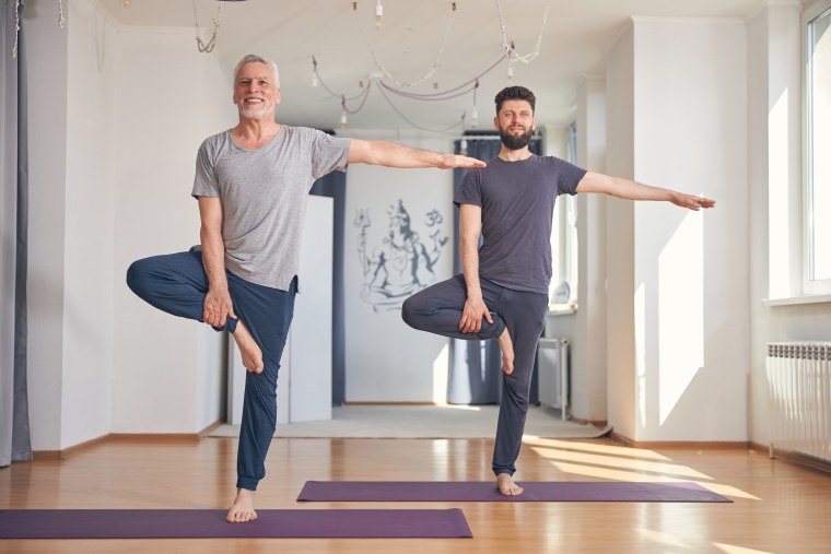 Dos hombres intentan mantener el equilibrio mientras realizan una pose de yoga.
