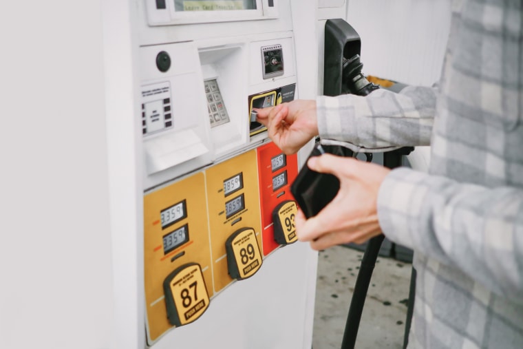 Un hombre inserta una moneda para adquirir gasolina.