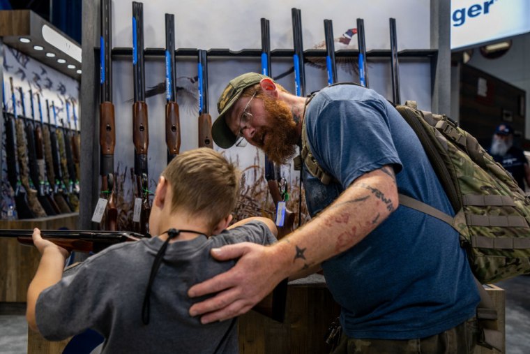 Chris Shelton, de 36 años, ayuda a su hijo Luke Shelton, de 7 años, a dirigir un arma de fuego en el Centro de Convenciones George R. Brown durante la convención anual de la Asociación Nacional del Rifle (NRA) el 28 de mayo de 2022 en Houston, Texas.