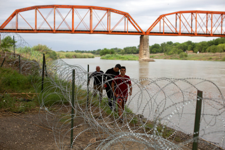 Tres migrantes de Cuba llegan a suelo estadounidense tras cruzar el río Grande en Eagle Pass, Texas, el domingo 22 de mayo de 2022.