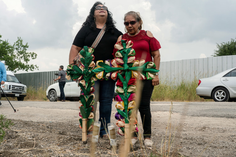 Los miembros de la comunidad local Debra Ponce, izquierda, y Angelita Olvera lloran después de colocar cruces y velas en el lugar donde los migrantes fueron encontrados muertos.