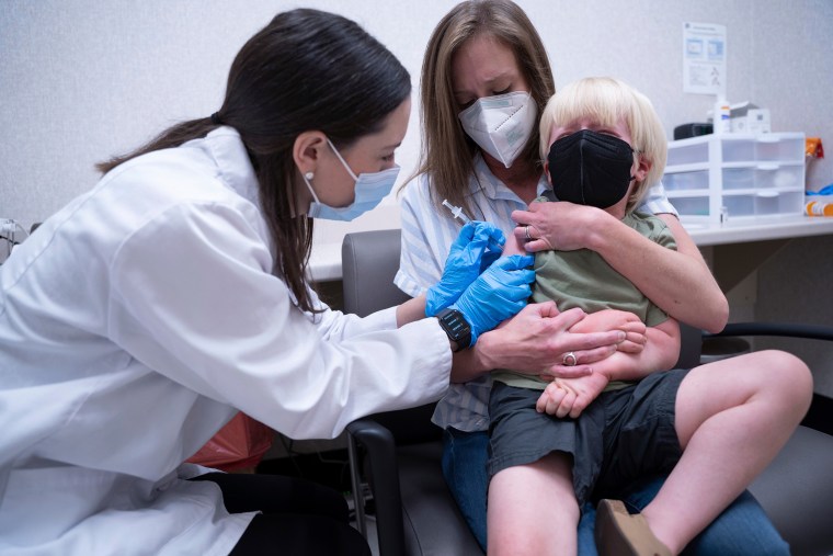 Pharmacist Kaitlin Harring, left, administers a Moderna COVID-19 vaccination to three-year-old Fletcher Pack, while he sits on the lap of his mother, McKenzie Pack, at Walgreens pharmacy Monday, June 20, 2022, in Lexington, S.C. (AP Photo/Sean Rayford)