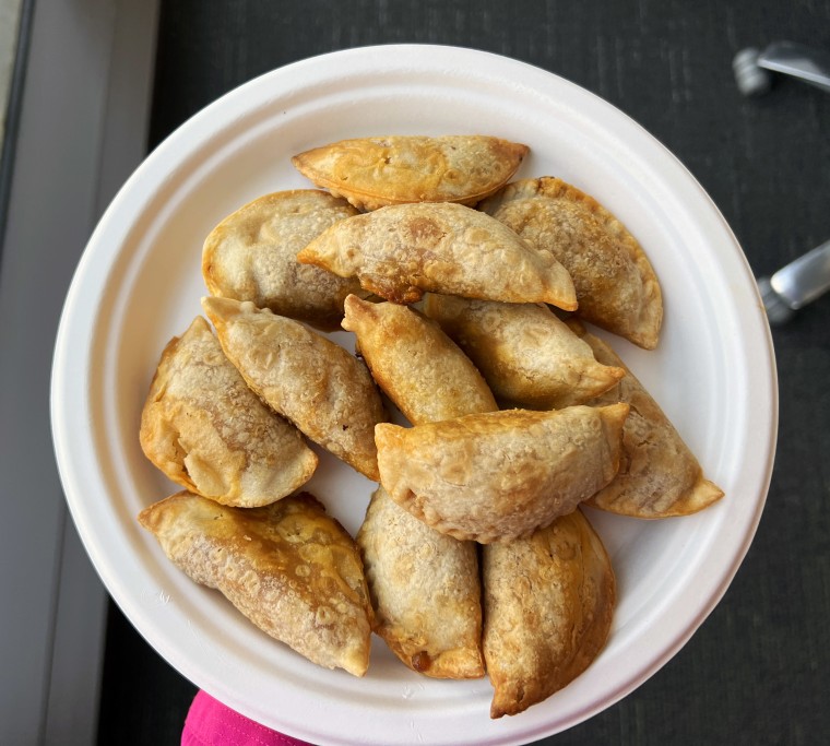 A pile of mini empanadas on a white plate.