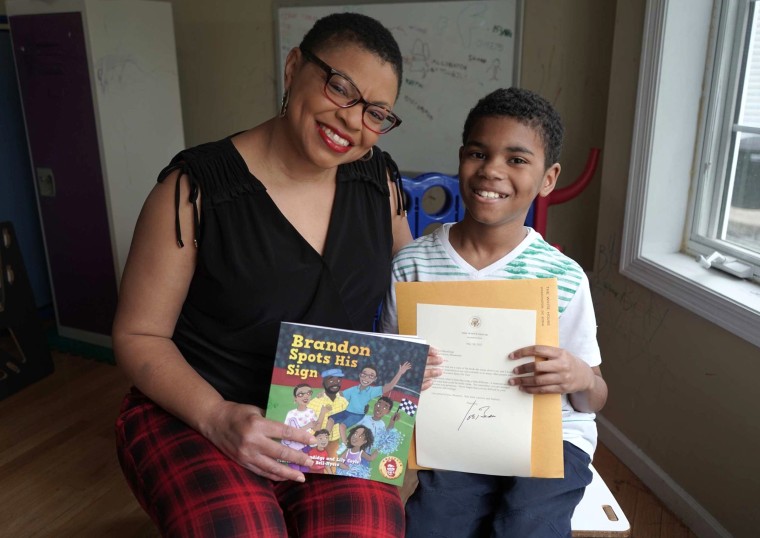 Sheletta Brundidge holds her book while her son, Brandon, holds a letter he received from President Joe Biden.