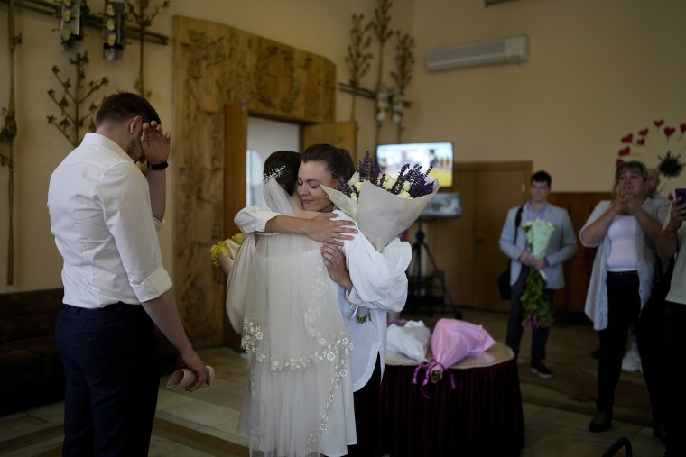 Kateryna Lytvynenko, centro, abraza a un pariente después de casarse con Ihor Zakvatskyi, izquierda, en Kyiv, Ucrania, el miércoles 15 de junio de 2022.