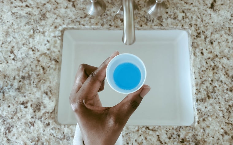 Woman Holds Cup of Mouthwash