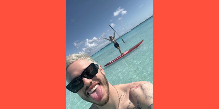 Davidson and Kardashian paddleboard in crystal blue waters on their vacation.