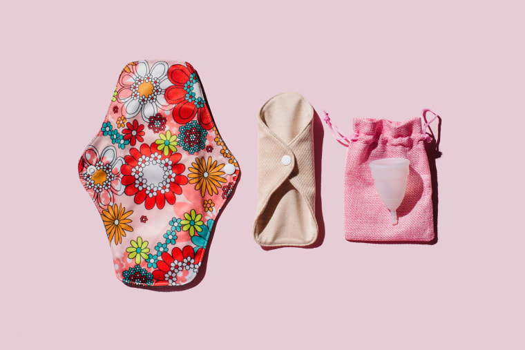 Reusable cloth menstrual pads and menstrual cup on pink background.