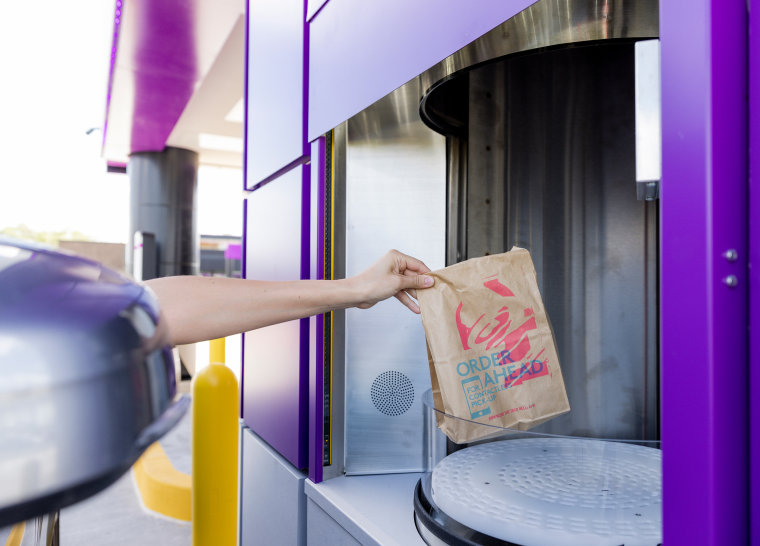 Customers at Taco Bell Defy pick up orders from a "proprietary vertical lift."