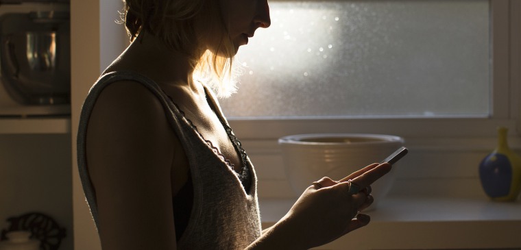 Silhouette of young woman looking at smart phone