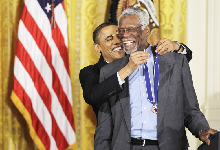 President Barack Obama reaches up to present a 2010 Presidential Medal of Freedom to basketball hall of fame member and former Boston Celtics coach and captain Bill Russell on Feb. 15, 2011, during a ceremony in the East Room of the White House.