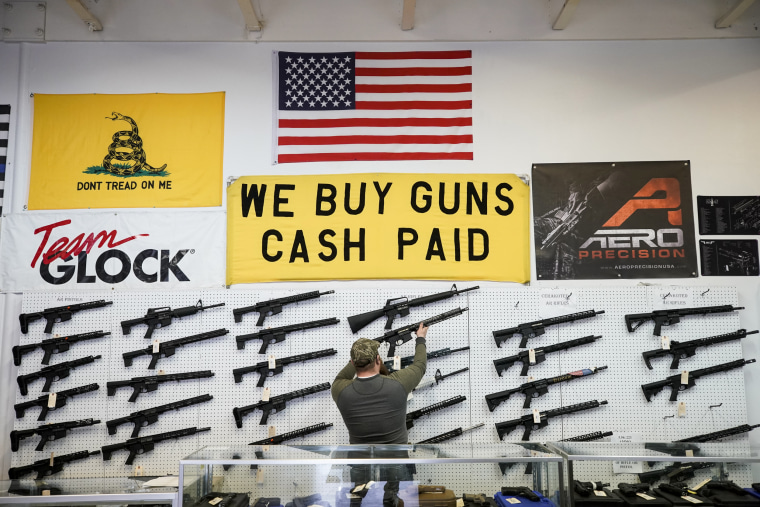 Image: A salesperson takes an AR-15 rifle off the wall at a store in Orem, Utah on March 25, 2021.