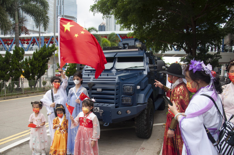 Patriots wave Chinese flags in front of an armored police vehicle during the celebrations on Friday. 