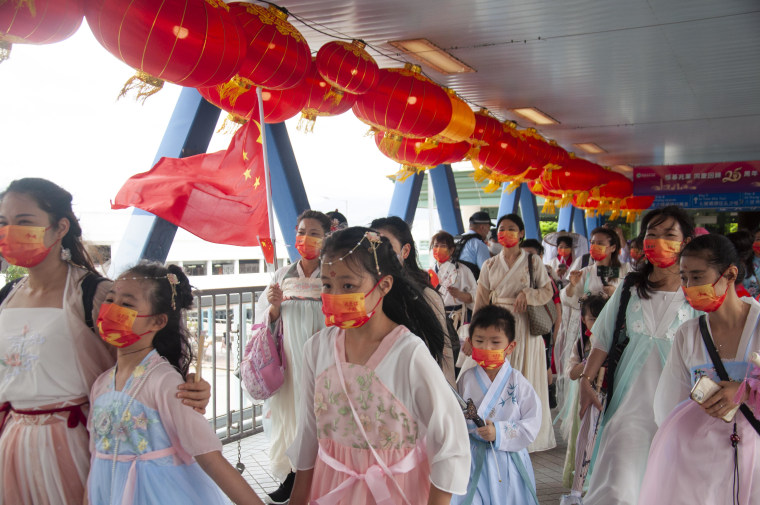 Children wave national flags as they move along the harbor in Hong Kong on Friday. 