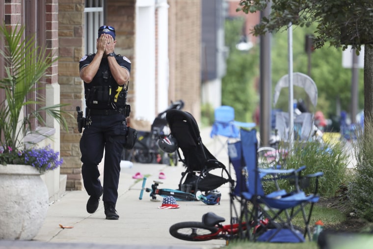 A Lake County police officer walks down Central Ave in Highland Park, Ill.