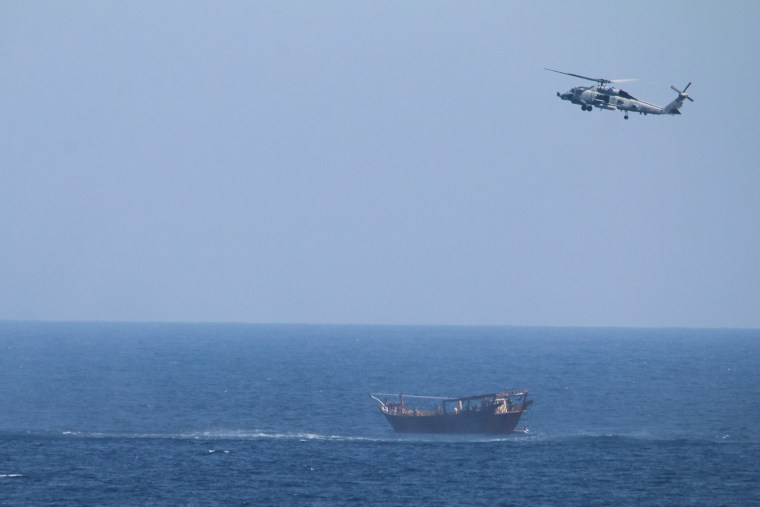 A U.S. Navy Seahawk helicopter flies over a stateless dhow