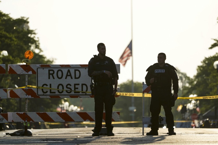 Two police officers stand their post on July 5, 2022, the day after a mass shooting in Highland Park, Ill.