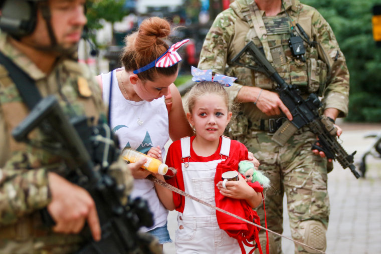 Law enforcement escorts a family away from the scene of a shooting at a Fourth of July parade in Highland Park, Ill.
