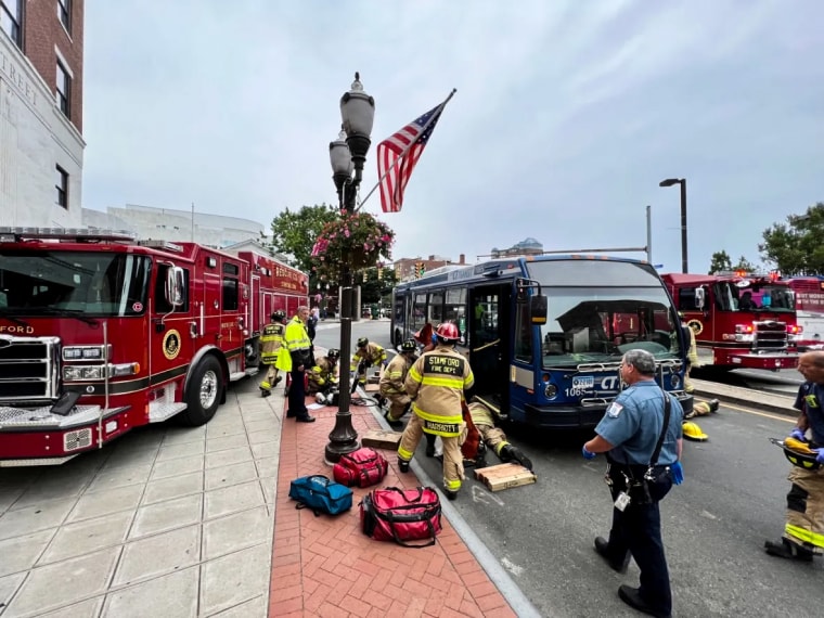 Image: The Stamford Fire Department responds to a woman trapped under the front axle of a tandem-style bus on July 5, 2022 in Stamford, Conn.