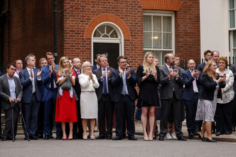Onlookers, including Carrie Johnson, and baby Romy, Culture Secretary Nadine Dorries and Scotland Secretary Alister Jack watch as British Prime Minister Boris Johnson addresses the nation to announce his resignation outside 10 Downing Street, on July 7, in London.
