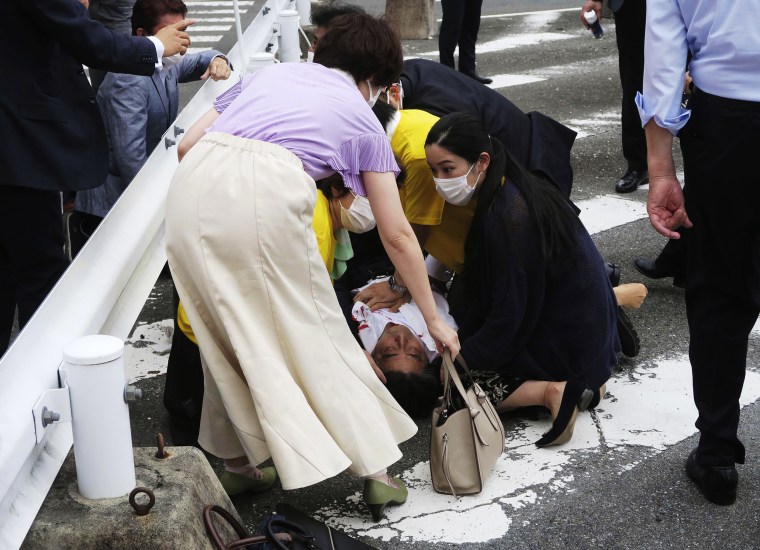Photos from the scene showed Shinzo Abe collapsed on the street with blood visible on his shirt, surrounded by security.