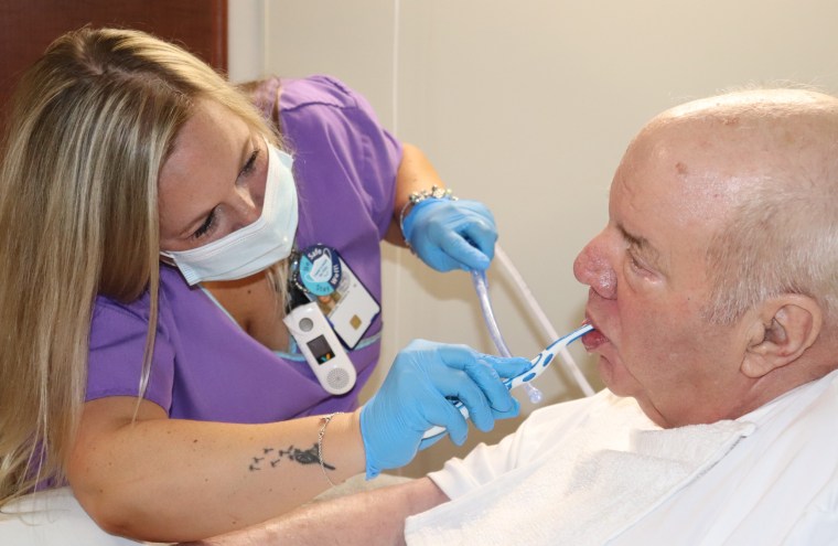 Nursing assistant Teresa Quarles brushes the teeth of James Massie, an Army veteran and a patient at the Salem Veterans Affairs Medical Center in Salem, Va., in June. The Salem VA reprioritized oral care to combat non-ventilator hospital-acquired pneumonia in 2016, and the program has since expanded across the Veterans Health Administration and is often cited as a model for all hospitals. 