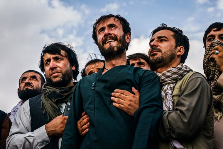 Ramal Ahmadi, center, is supported by family members as he weeps looking up jet fighters circling the skies above as the U.S. withdrawal concludes during a mass funeral for the 10 people the family said were killed in a U.S. drone strike in Kabul, Afghanistan, on Aug. 30, 2021.