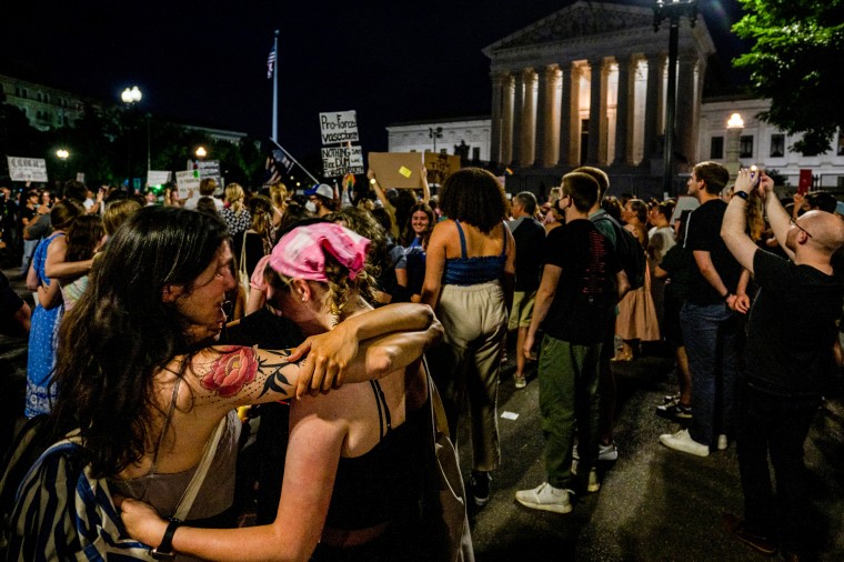 Protesters embrace at a candlelit vigil in front of the Supreme Court to denounce the court's decision to end federal abortion protections on June 26, 2022.
