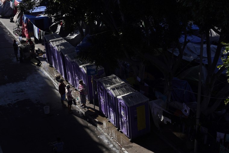 Migrants talk in front of portable toilets in a camp in Tijuana, Mexico, on Nov. 8.