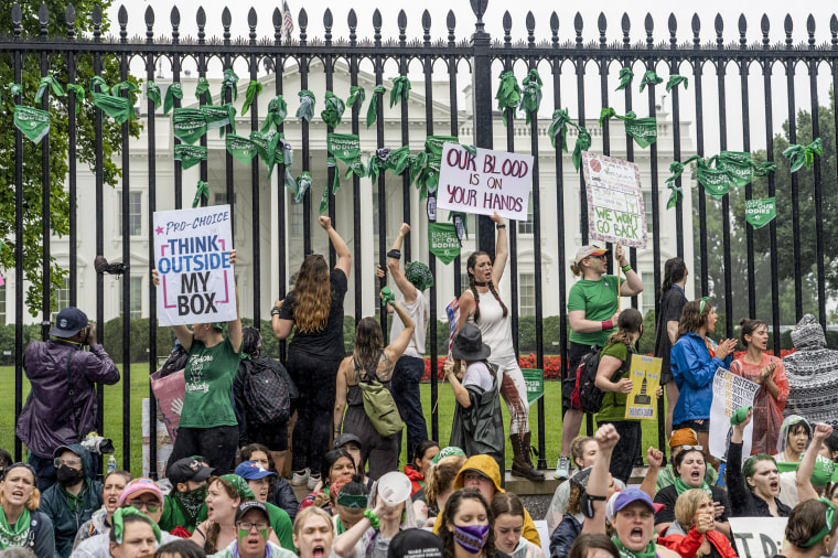 Abortion-rights protesters shout slogans after tying green flags to the fence of the White House during a protest to pressure on the Biden administration to protect abortion rights on July 9, 2022.