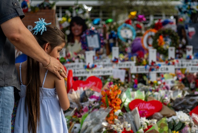 Image: Seth Garza and his daughter, Lilly, pause at a memorial dedicated to the 19 children and two adults killed during a mass shooting at Robb Elementary School in Uvalde, Texas, on May 31, 2022.