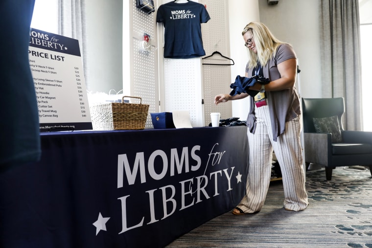 Jara Jeffries organizes Moms for Liberty apparel for sale in the hallway during the organization's inaugural summit on July 15, 2022, in Tampa.
