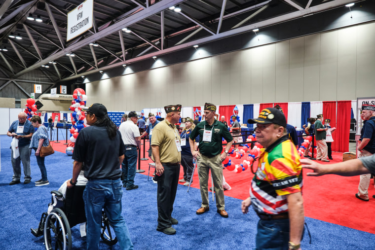 Michael Braman, center, speaks with Tom McClernon on the floor of the VFW Convention in Kansas City, Mo., on July 16, 2022.