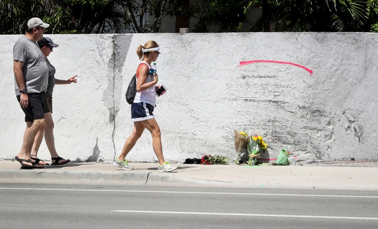 People walk past the site of a crash on May 12, 2018, where a Tesla Model S sedan crashed into a concrete wall in Ft. Lauderdale, Fla.