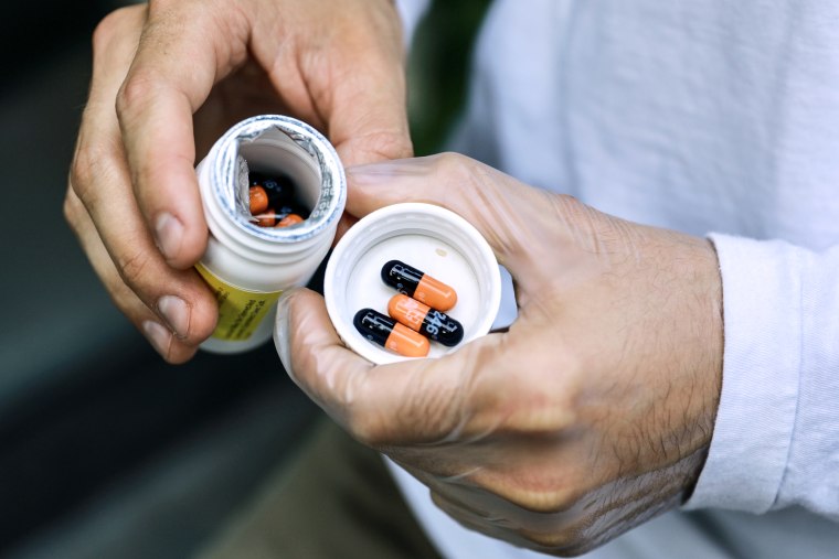 Luke Brown holds his bottle of TPOXX pills.