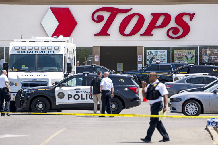 Law enforcement officials patrol the scene of a mass shooting at Tops Friendly Market