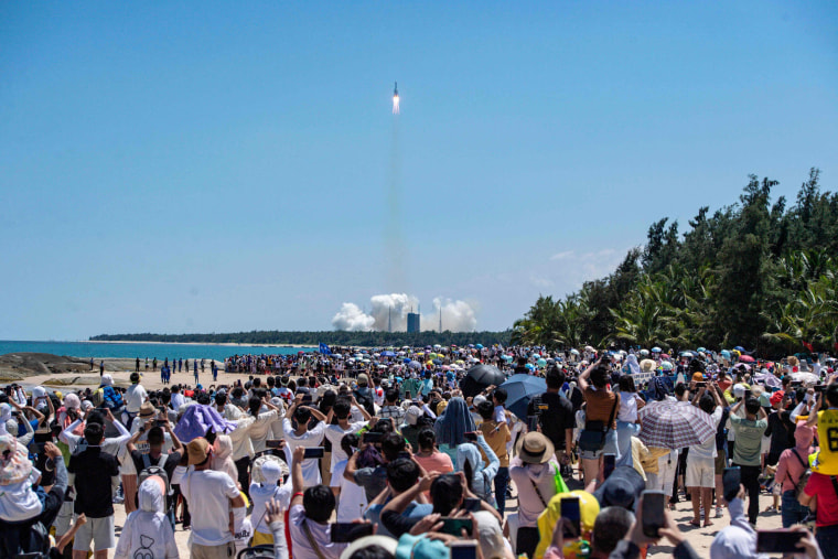 Onlookers watch the launch of a rocket