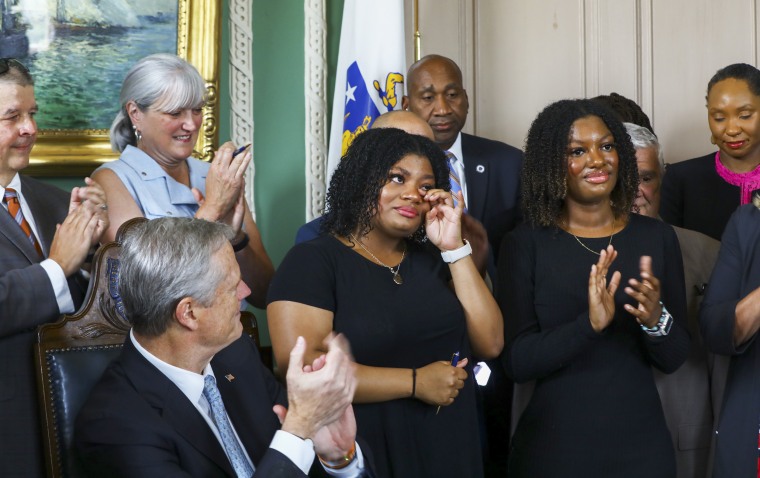 Image: Deanna Cook wipes away tears after Governor Charlie Baker signed the CROWN Act at the Massachusetts State House on July 26, 2022 in Boston.