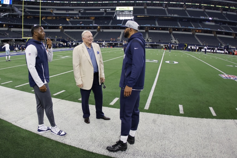 Image: Dallas Cowboys owner Jerry Jones, center, talks with Dallas Cowboys' Amari Cooper, left, and quarterback Dak Prescott, right,  in Arlington, Texas on Aug. 29, 2021.