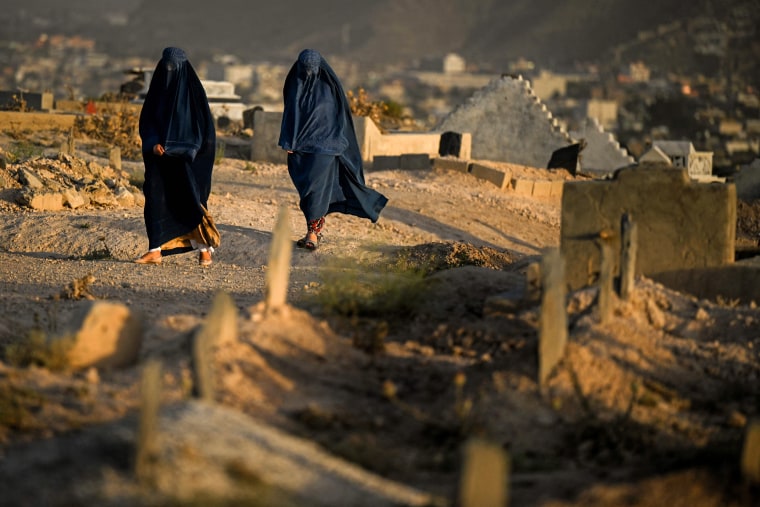 Women walk along a cemetery in Kabul on July 19, 2022.