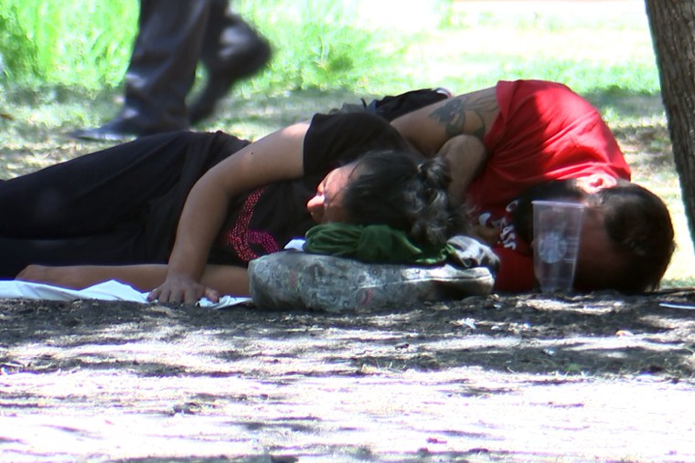 Migrants rest at a park during a hot day in July, in San Antonio.