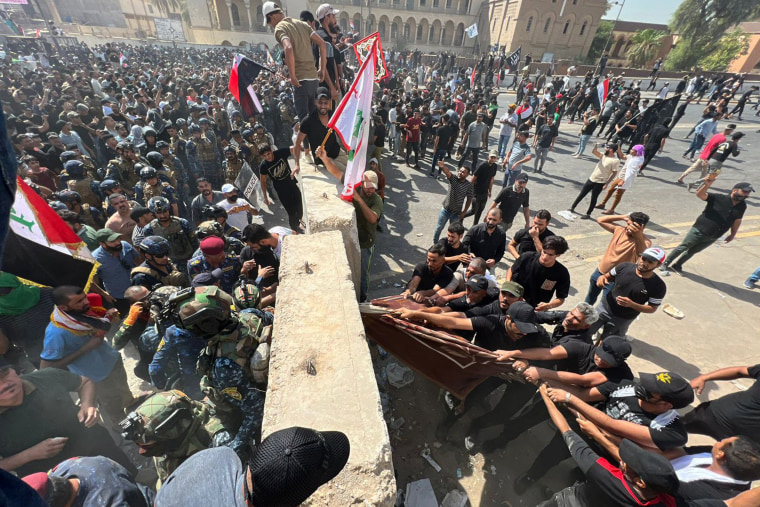 Protesters try to remove concrete barriers and cross the bridge towards the Green Zone