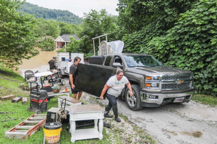 A couple moves belongings away from flood waters