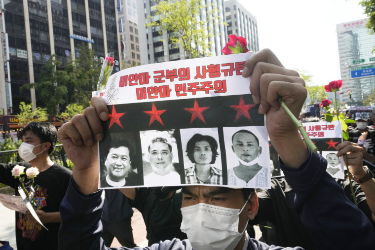 A protestor holds a sign with photos of the Myanmar activist execution victims